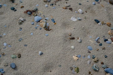 Close-up view of sand and small pebbles on a beach shore in natural sunlight.