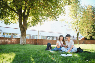 Students using smartphones and studying outdoors on campus