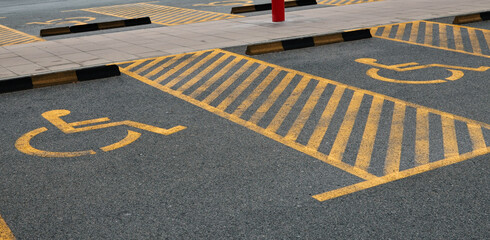Yellow markings designating accessible parking spots on asphalt surface. The concept represents accessibility, inclusion, and organized infrastructure