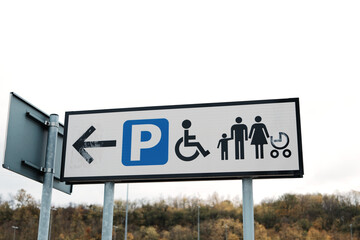 Outdoor sign showing directions for parking areas including family and accessible zones. The concept conveys guidance, inclusivity, and organization