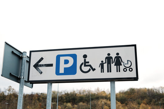 Outdoor sign showing directions for parking areas including family and accessible zones. The concept conveys guidance, inclusivity, and organization