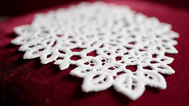 White doily on soft red velvet, close-up of fabric texture.