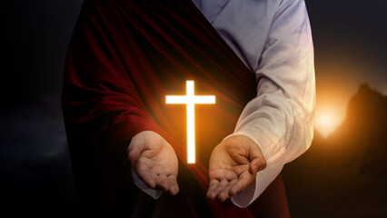 Jesus Christ raising his hand and praying with the Christian cross with dark dramatic sky background. Concept of Christianity, religious, faith, Jesus, or belief