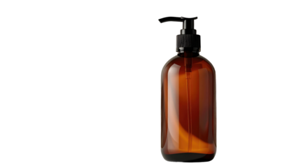 A translucent brown bottle with a black pump dispenser is isolated on a black background, with the bottle slightly right of center