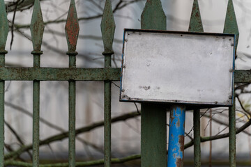 Pusta metalowa tabliczka na starym zardzewiałym ogrodzeniu © Kacper