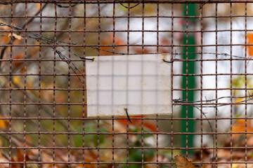 Pusta tabliczka na zardzewiałej siatce z drutem kolczastym © Kacper