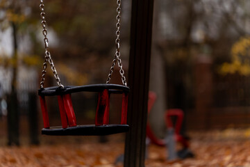 Pusta huśtawka dla dzieci na jesiennym placu zabaw © Kacper