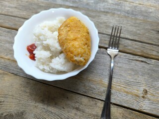 Kyiv cutlet with white rice on a plate on a wooden table