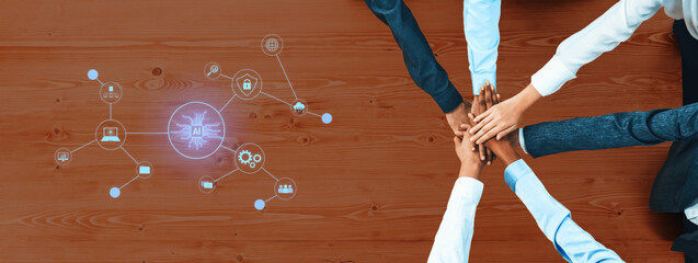 A group of diverse individuals are joining hands on a wooden table, symbolizing teamwork and collaboration, with digital icons representing technology and communication. Trope