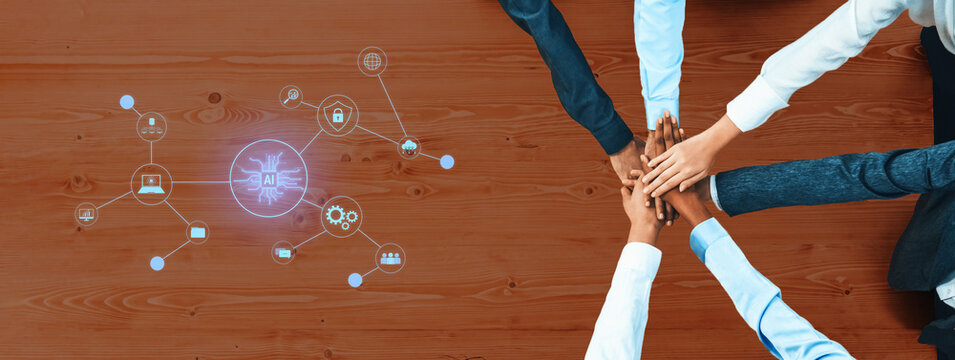 A group of diverse individuals are joining hands on a wooden table, symbolizing teamwork and collaboration, with digital icons representing technology and communication. Trope