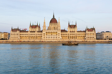 Fototapeta premium Old-fashioned paddle boat moving along the Danube river in front of the 1905 Gothic Renaissance style Parliament seen from Buda during the afternoon golden hour, Budapest, Hungary