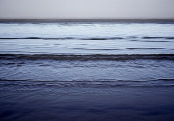 Tranquil ocean view with gentle waves under a muted sky background