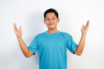 A cheerful Asian man wearing a blue shirt expressing happiness with outstretched open hands in a...