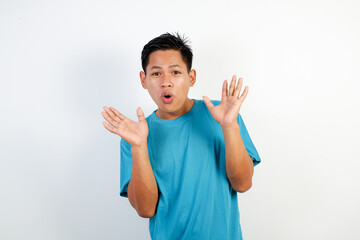 A young Asian man wearing a blue T-shirt raises his hands in a surprised, playful pose.