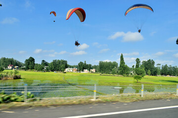 Paragliding over paddy fields of Anantnag Kashmir India Tourists paragliding 3 pm 6 june 2025  with view of Himalayan mountain range.