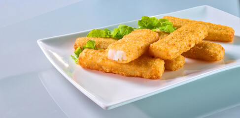 Fischstaebchen auf Porzellanplatte mit Salatdeko