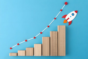 Wooden bar chart with trend line and paper rocket