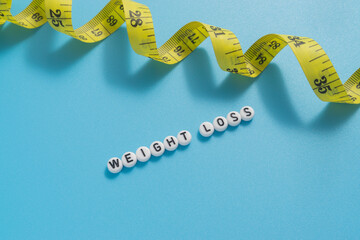 Yellow tape measure with text Weight Loss on light blue background