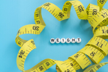 Yellow tape measure with text Weight on light blue background
