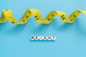 Yellow tape measure with text Weight on light blue background