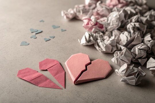 Broken origami heart in pieces symbolizing loss and sadness