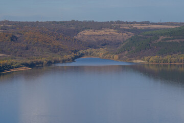 Scenic landscape of Bakota Bay in Khmelnytskyi region, Ukraine. Calm river, brown hills, and fields create a peaceful view of the Dniester Canyon area in autumn light.