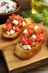 Tasty bruschettas with tomatoes, mozzarella cheese and basil served on wooden table, closeup