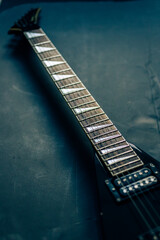 Perspective view of electric guitar on dark textured surface, elegant lighting emphasizing lines and reflections.