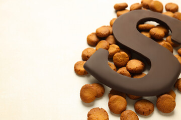 Sinterklaas (Saint Nicholas) Day. Chocolate letter S and kruidnoten cookies on light background,...