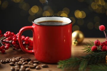 Aromatic coffee in red mug, beans, berries and fir tree branches on wooden table against black...