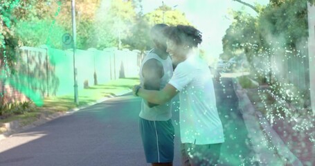 Hugging two men wearing sportswear and watch, embracing on quiet street with green mist