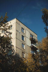A corner of a residential building framed by vivid golden autumn leaves under a deep blue sky, showcasing the harmony of urban design and seasonal nature.