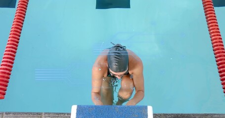 Preparing female swimmer bracing block in pool amid red ropes wearing dark swimsuit cap  and  goggle