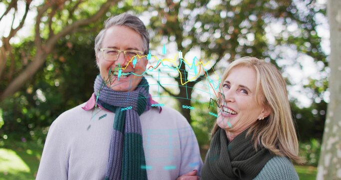 Standing couple linking arms smiling in park wearing scarves, holographic charts 3000,4000,5000