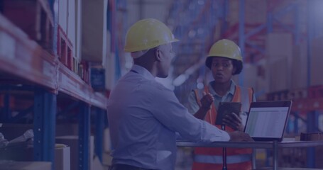 Inspecting staff talking in warehouse aisle with tablet and laptop on cart, shirt, vest, hard hats