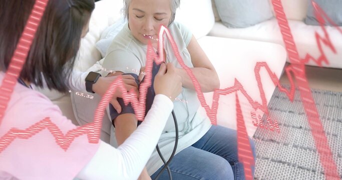 Receiving senior woman in green top having blood pressure cuff applied at home, with ECG overlay