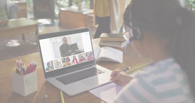 Taking notes girl wearing headset, striped top, at home study with laptop and notebook, copy space