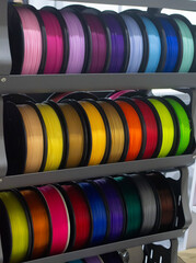 Many spools with multi-colored plastic for 3D printing. Spools with pink, red, burgundy, purple, yellow, orange blue plastic wire for 3D printer. Components for 3D printing. Accessories for 3D printer