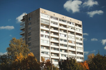 A corner of a residential building framed by vivid golden autumn leaves under a deep blue sky, showcasing the harmony of urban design and seasonal nature.