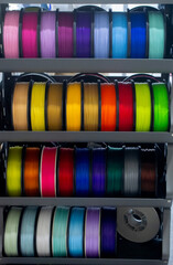Many spools with multi-colored plastic for 3D printing. Spools with pink, red, burgundy, purple, yellow, orange blue plastic wire for 3D printer. Components for 3D printing. Accessories for 3D printer