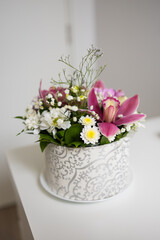 Elegant floral bouquet with pink lilies and daisies in patterned box. Warm emotions, freshness, and natural harmony.