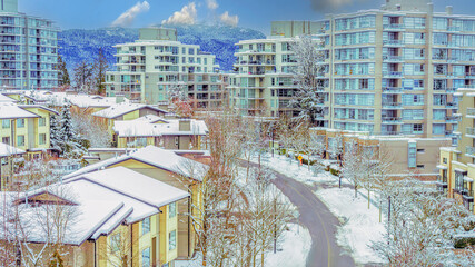 Snowy rooftops at a BC residential suburb with mountain backdrop.