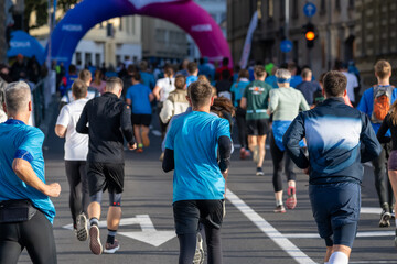 Group of male and female runners participating in a marathon event on city streets of Ljubljana during bright daylight