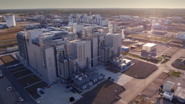 The drone flies over a large industrial complex. Warm evening light highlights pipes, structures, and production buildings from an elevated viewpoint at BASF Schwarzheide.
