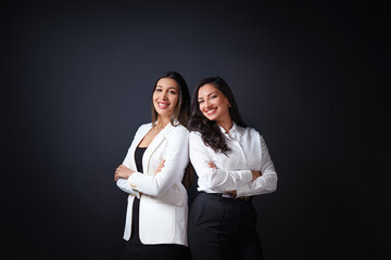 Portrait of two business people. portrait of two young successful business women smiling with joy while standing against neutral background.