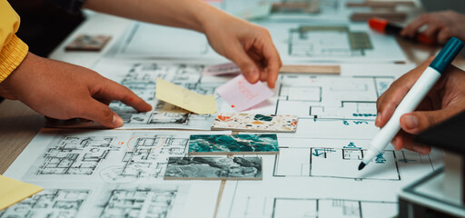 Hands reach for notes and sketches in a vibrant workspace, showcasing collaboration and creativity in project planning and design. Various materials highlight teamwork efforts. SACTR