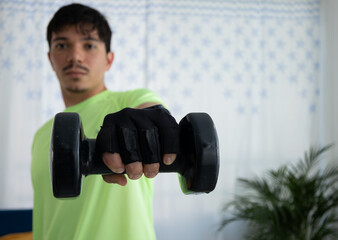 Man exercising in the living room of his home with one arm extended, holding a dumbbell. Concept of strength, balance, training, and a healthy lifestyle