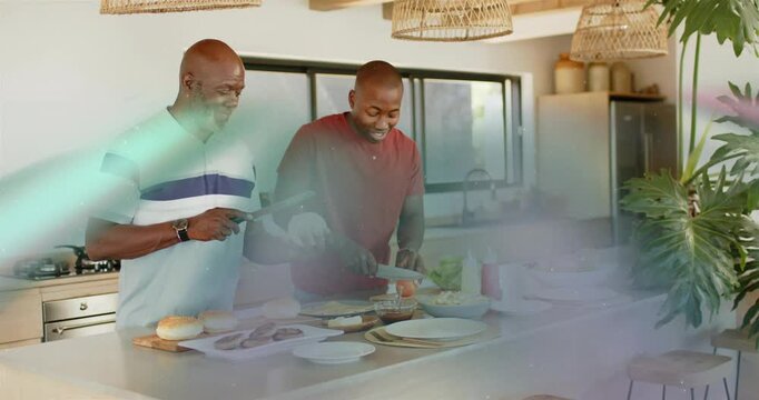 Dad handing bun nudging son chopping tomato and making burger for food, flare sweeping over hands