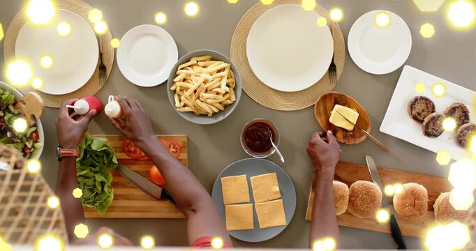 Son reaching lettuce father lifting patties building burgers for meal gold bokeh moving over hands