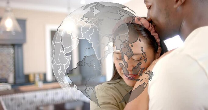 Globe appearing, obscuring faces while couple holding embrace in kitchen, aiding ads